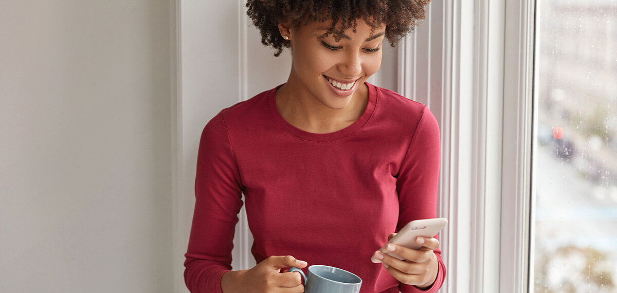 Woman smiling while looking at mobile phone screen.